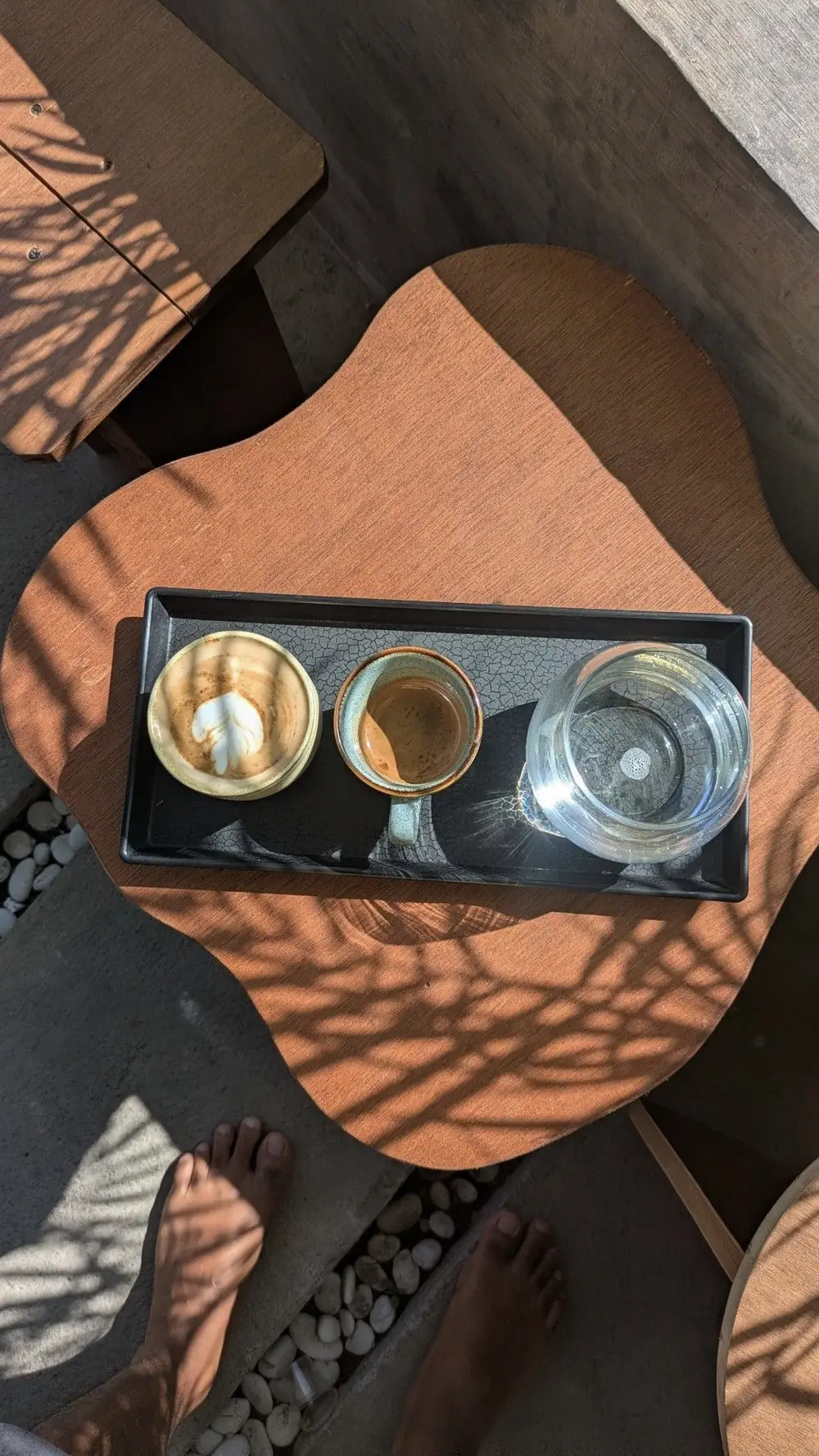 Latte, espresso and water on a tray in the sun