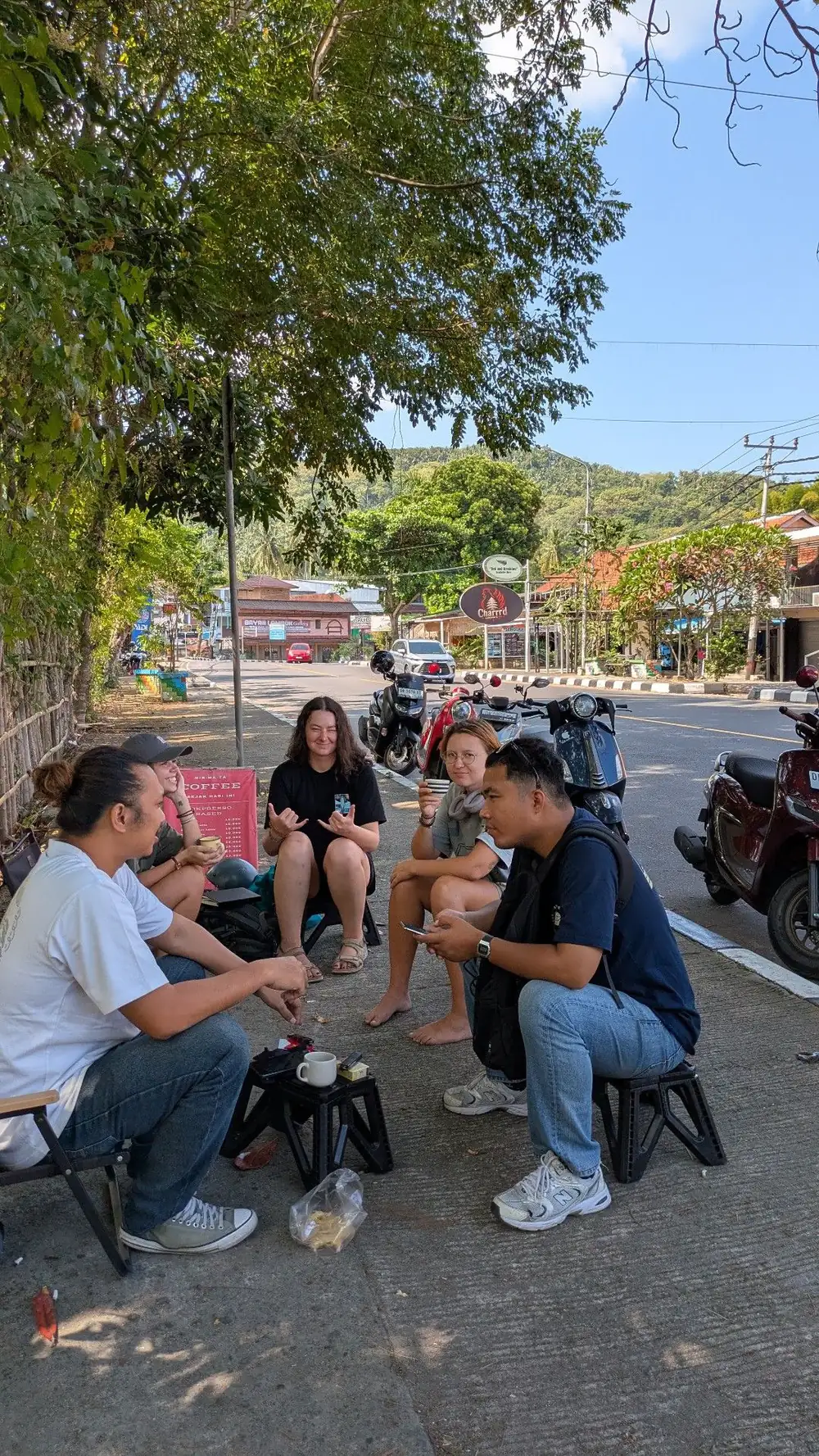 Customers on stools chatting on the street in Senggigi